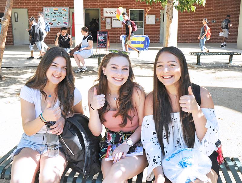 Three students smiling and giving the thumbs up.