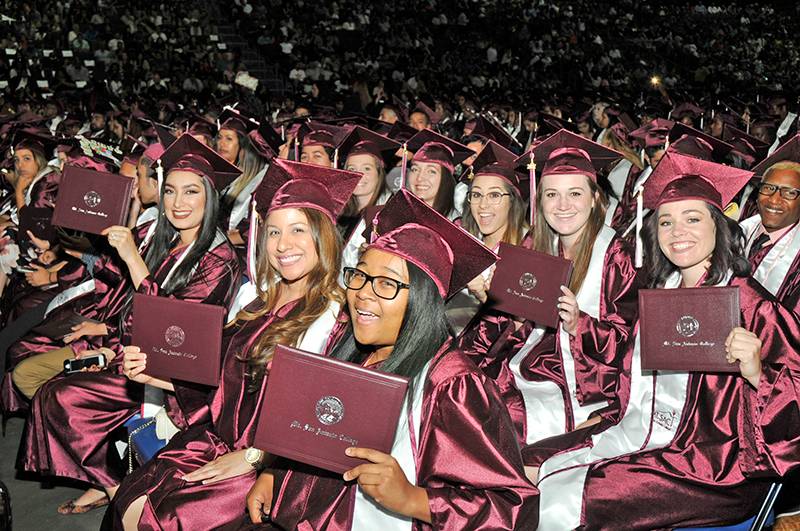 graduates holding up their diplomas