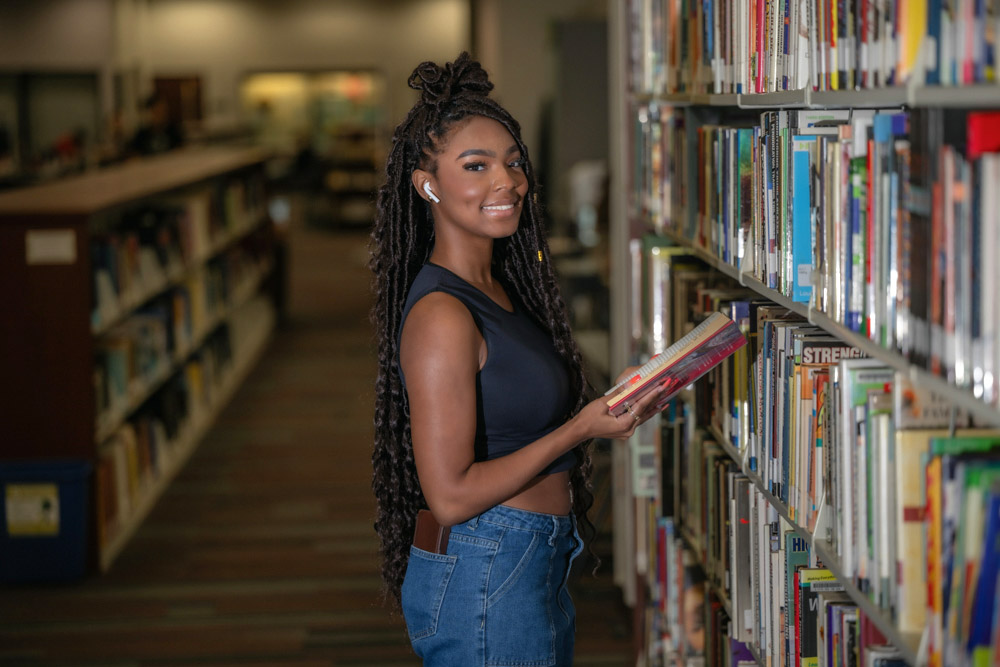 Amani Martin looks at book in the library