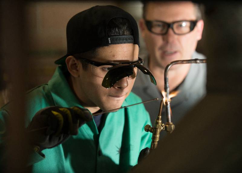 A student welds as the teacher looks on