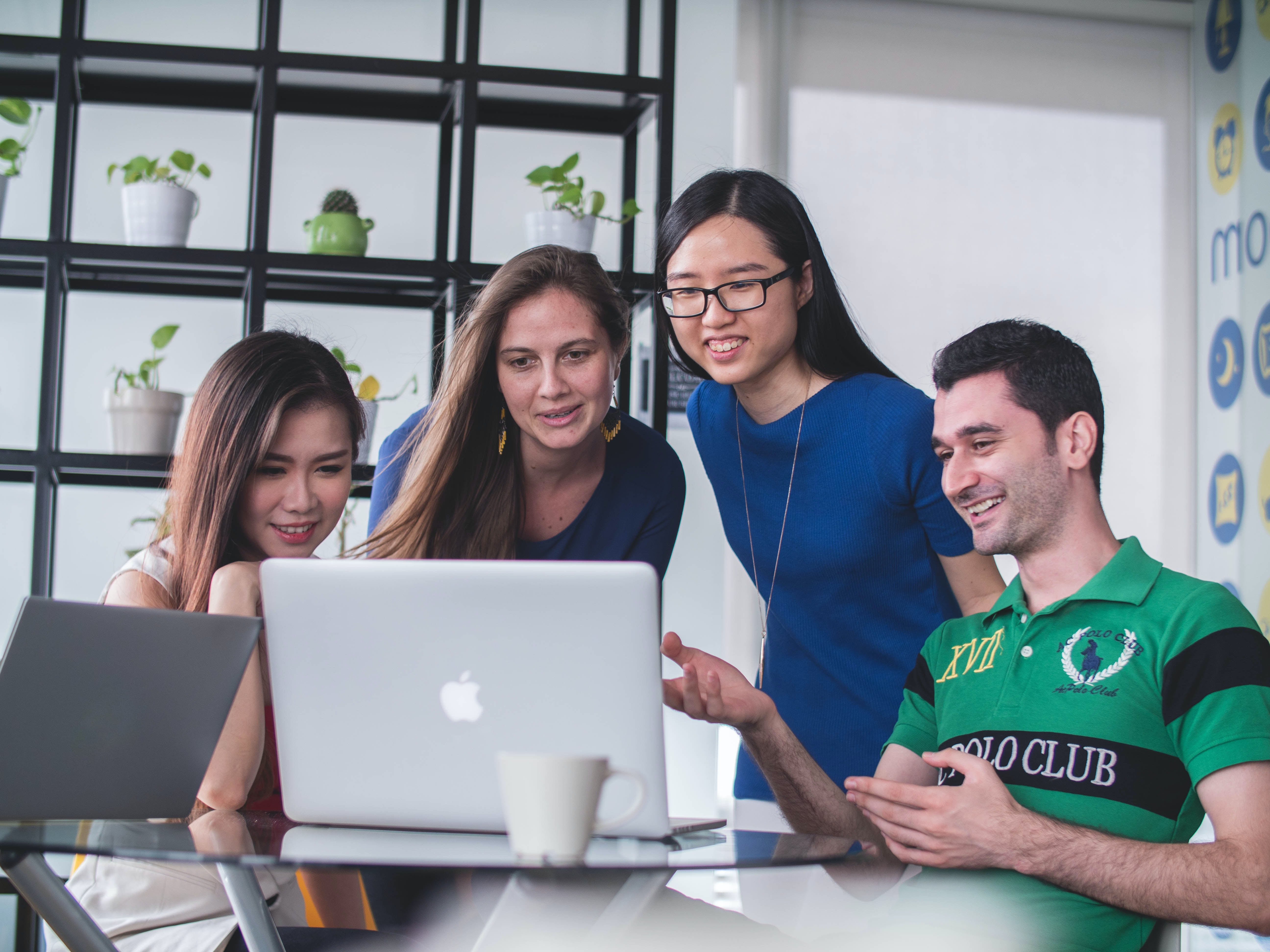 four students working together in front of a computer