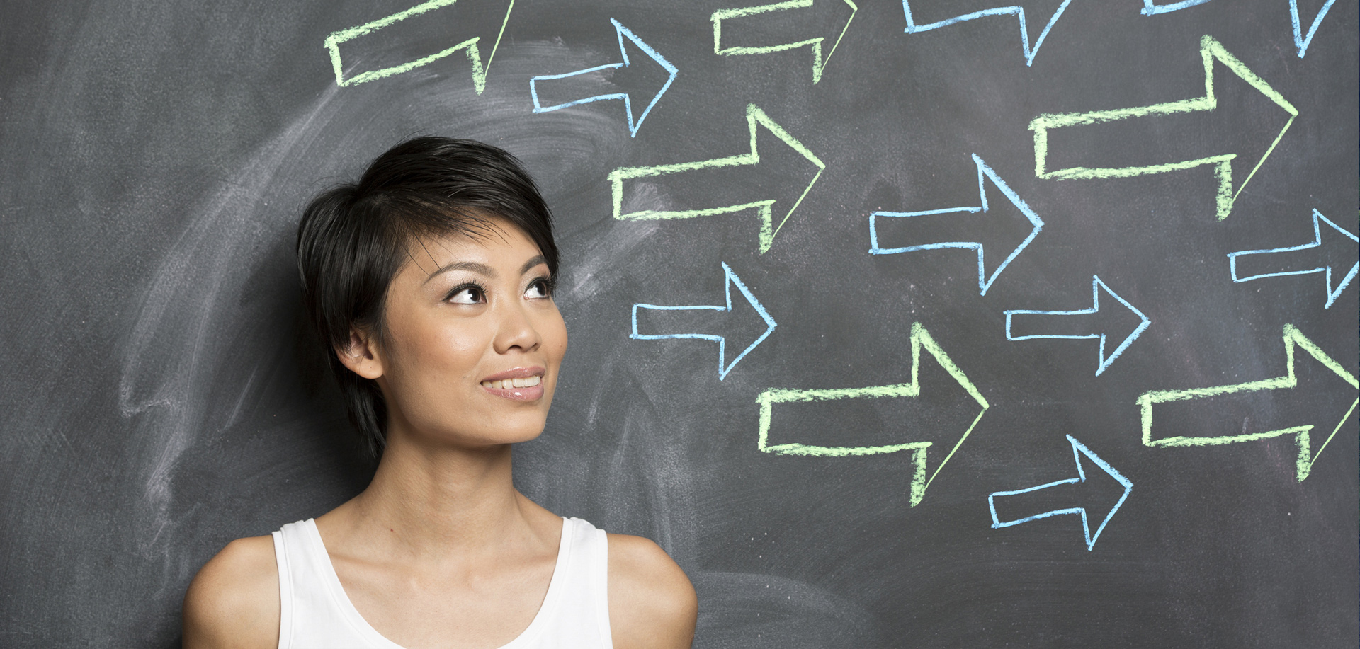 A photo of a young woman in front of a chalkboard with arrows drawn pointing in the same direction