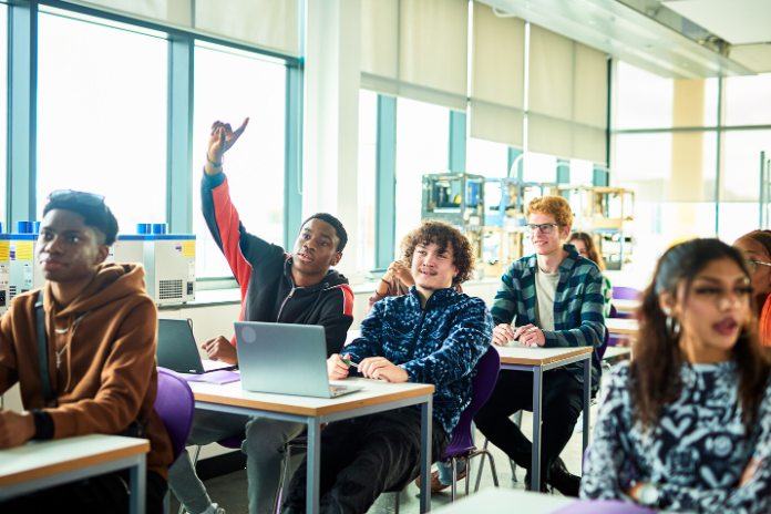 Young black boy raising his hand in class