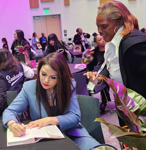author signs book for excited woman