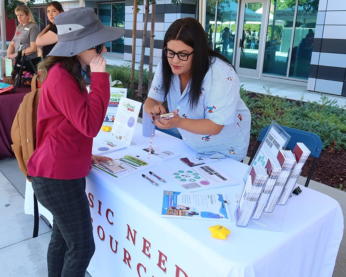 A rep for Mt. SAC's Basic Needs Resources Program shows a student some information.