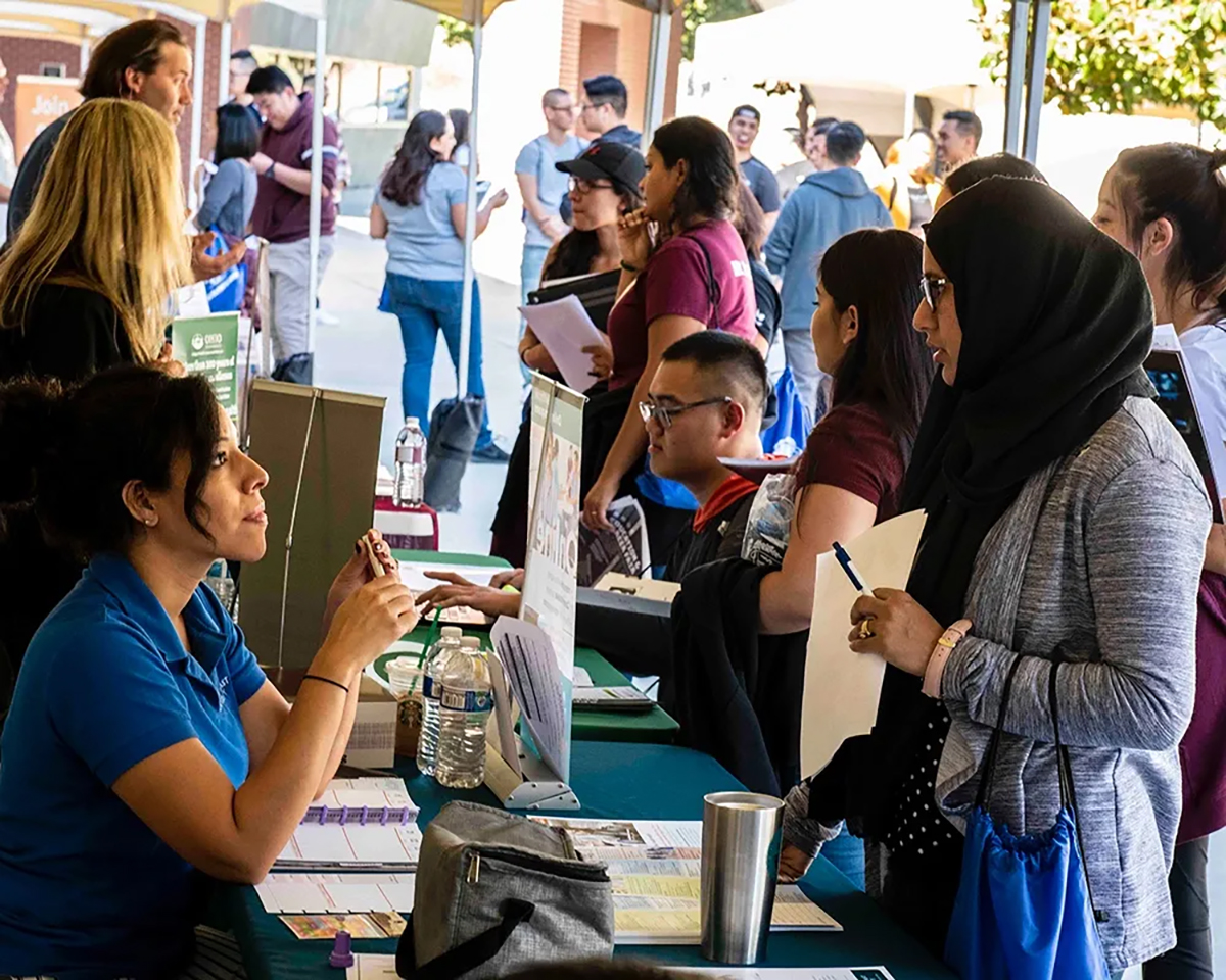 Students get information from volunteers at a booth at a Wellness fair event.