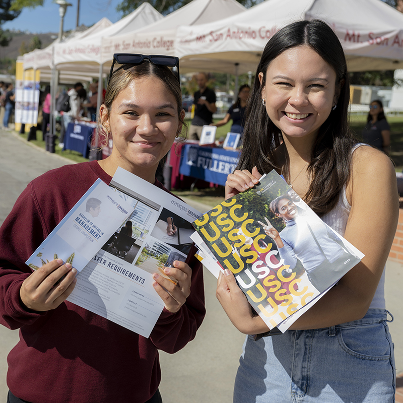 Two students holding reading material from a transfer fair.