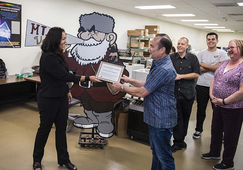 Gabby Sesma hands award to Print Services staff