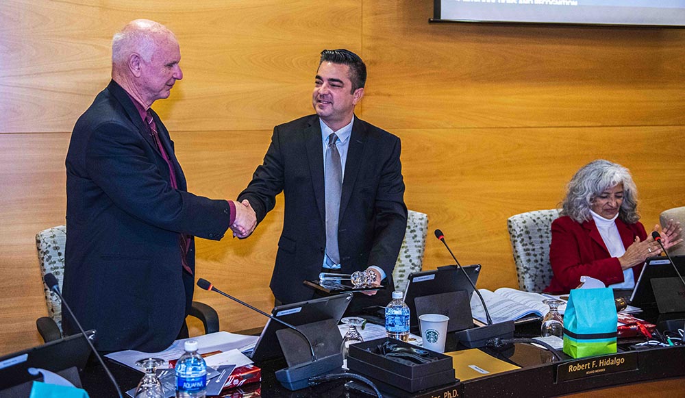 Dr. Scroggins (L) presents Trustee Hidalgo with a gavel for his service as board president