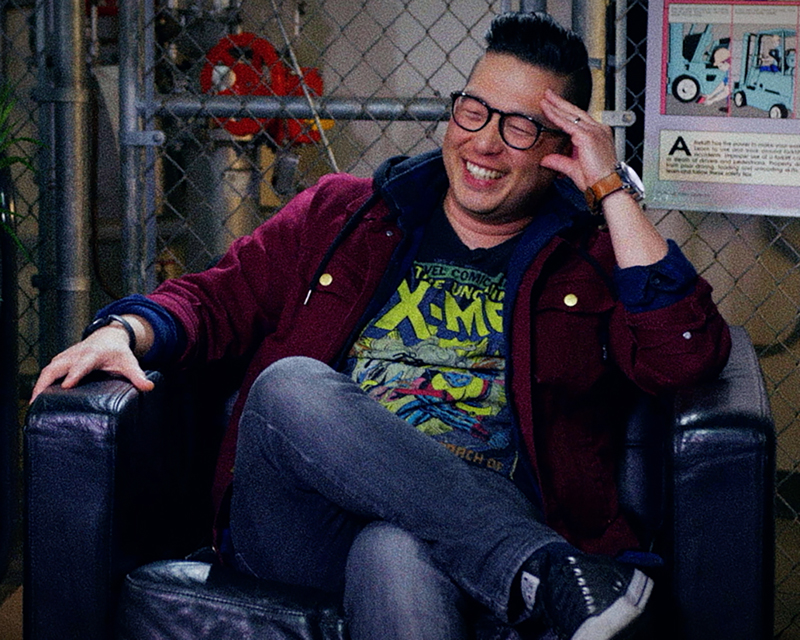 James Koh sits in a chair and smiles.