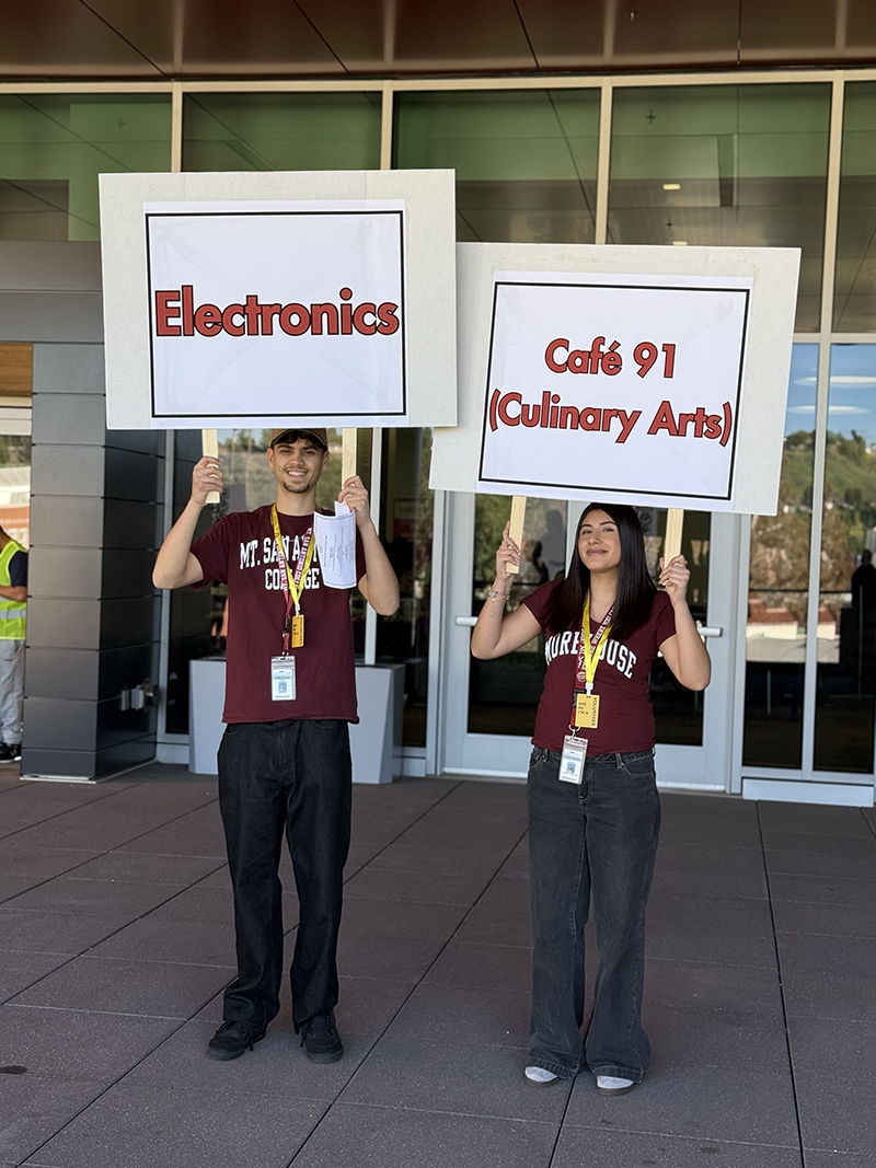 Two students hold their tour guide signs above their heads.