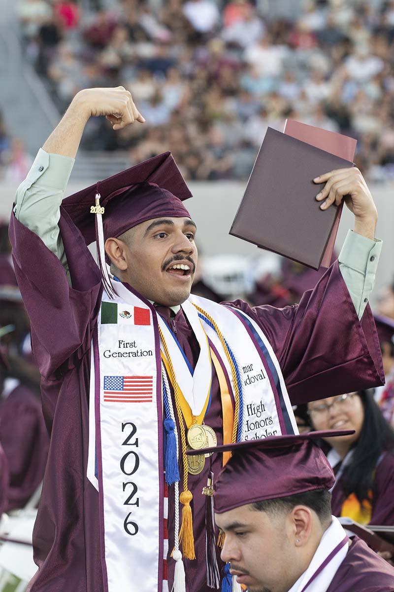 A Mt. SAC graduate stands and points to his diploma at commencement.
