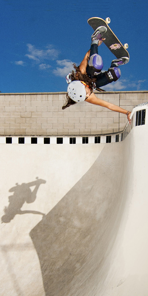 A skateboarder performs a handstand trick.