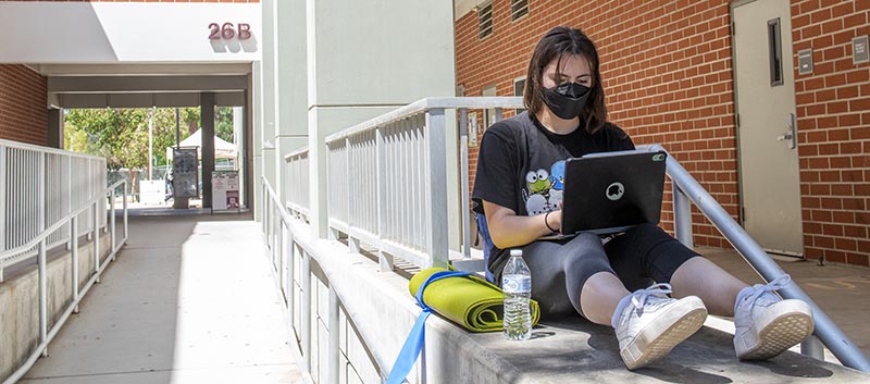 Student studies outside wearing mask