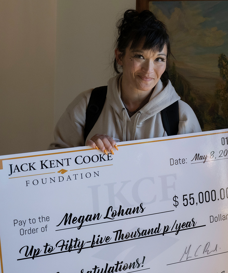 Megan Lohans holds up a scholarship check.