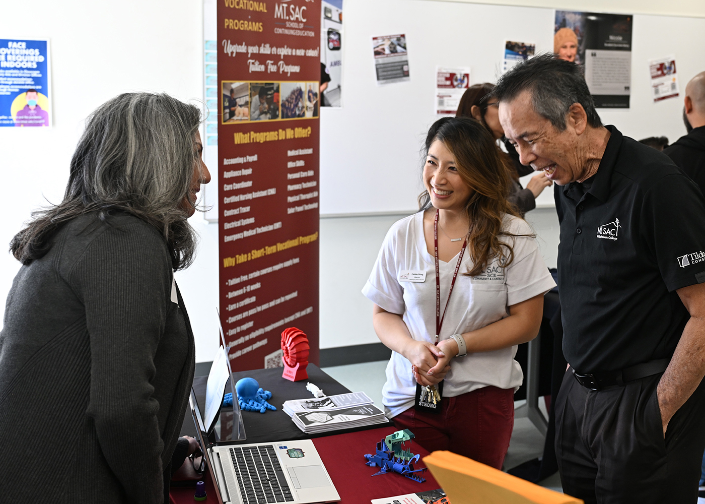 A group of people share information at a booth at the School of Continuing Education Open House.