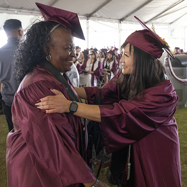 A pair of graduates enjoy a moment at the 2025 Commencement ceremony.