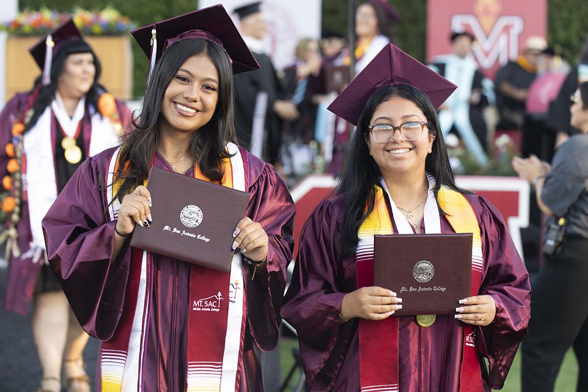 Two Mt. SAC graduates hold up diplomas at commencement in 2026.