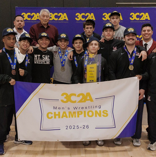 The Mt. SAC Men's Wrestling team poses with its state championship banner.