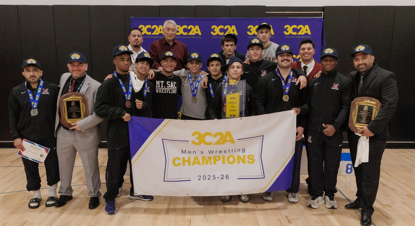 The Mt. SAC Men's Wrestling team poses with its state championship banner.