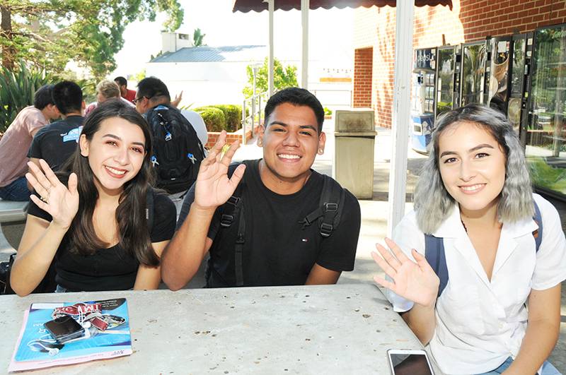 three students waving