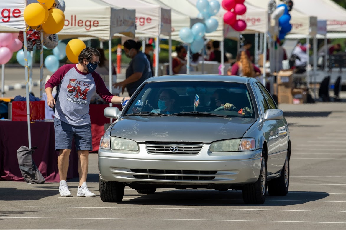 Staff member giving gift to grad in car