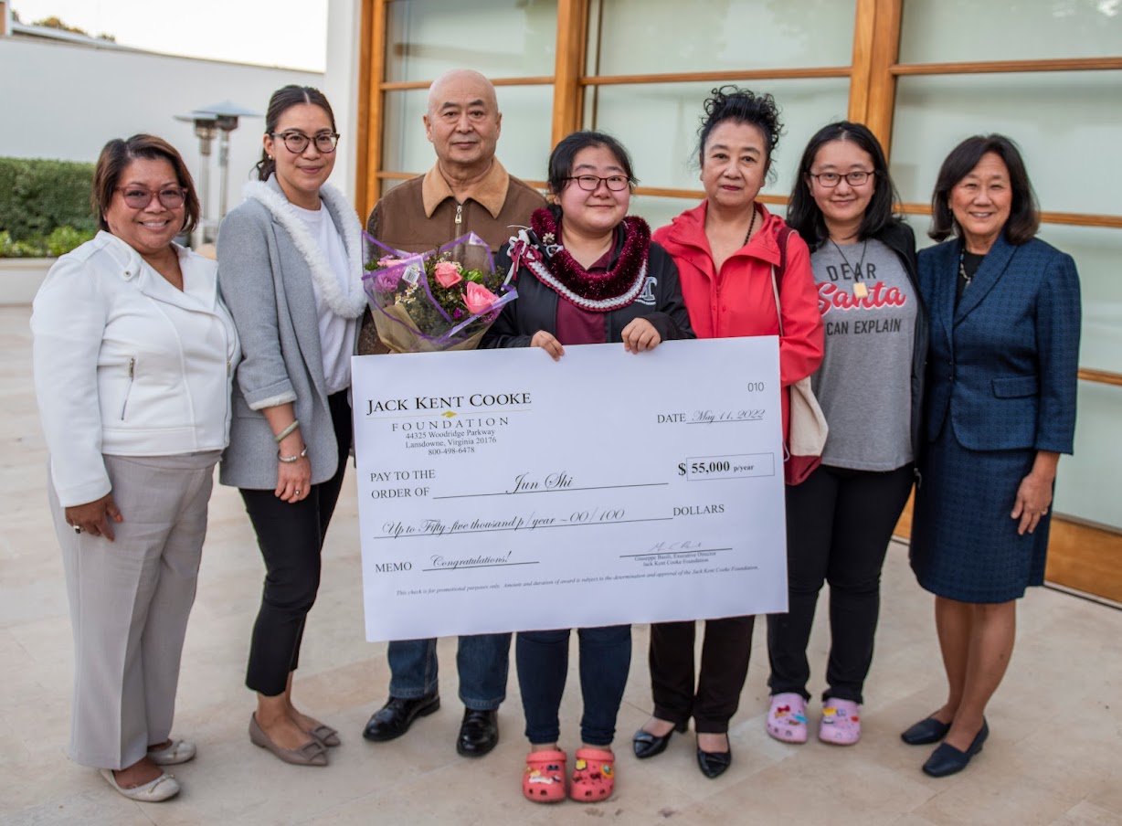 Group of men and women posing with student holding check