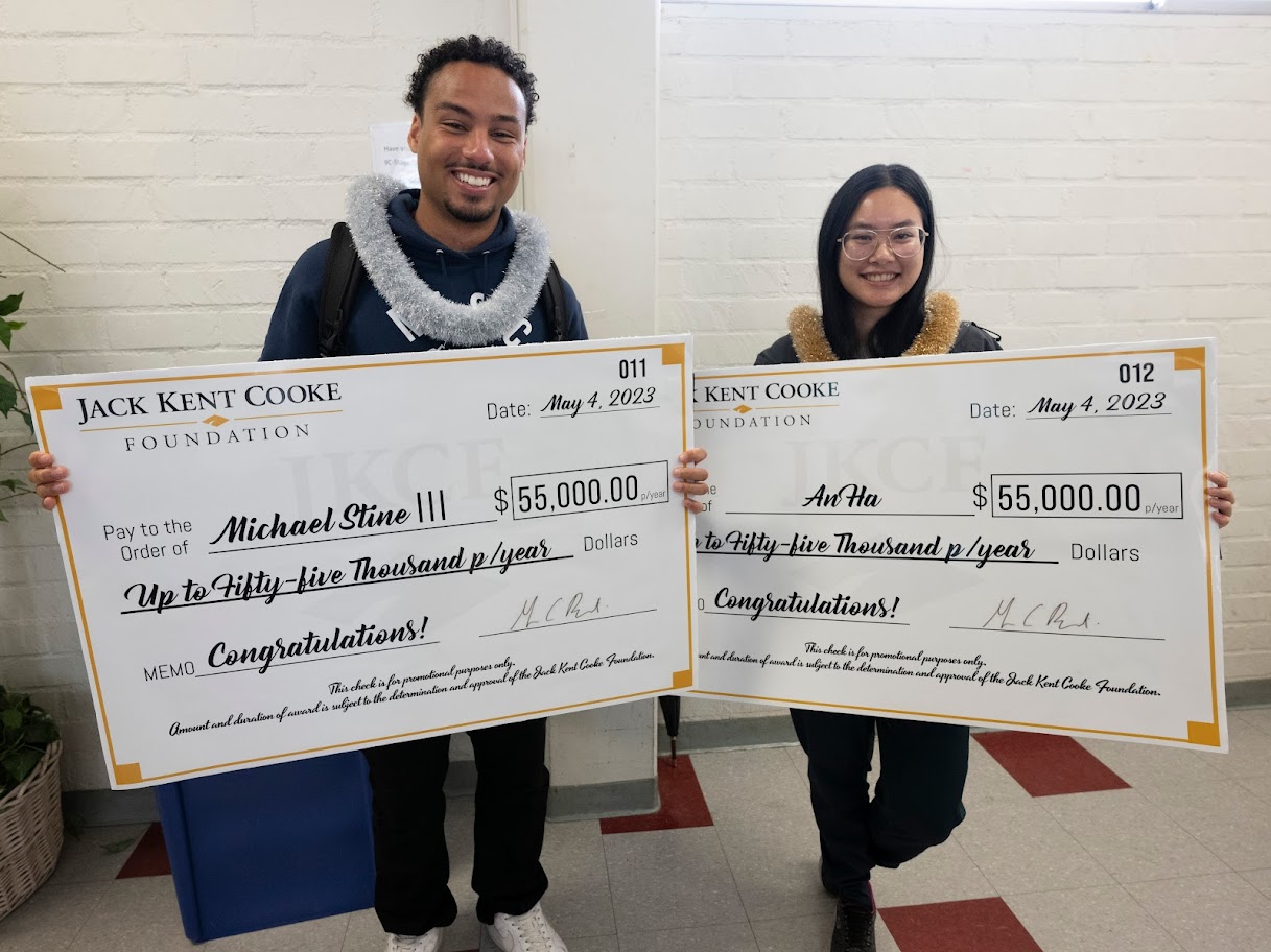 Male student and female student hold oversized checks