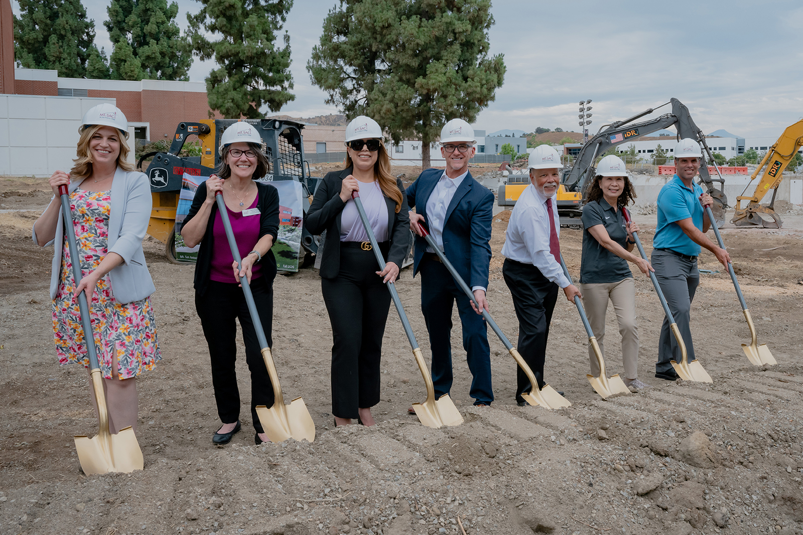 Men and women pretend to move dirt with gold shovels