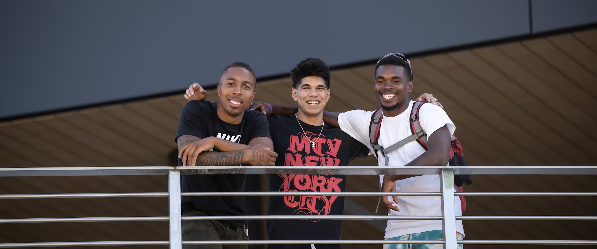 Three young men stand and smile 