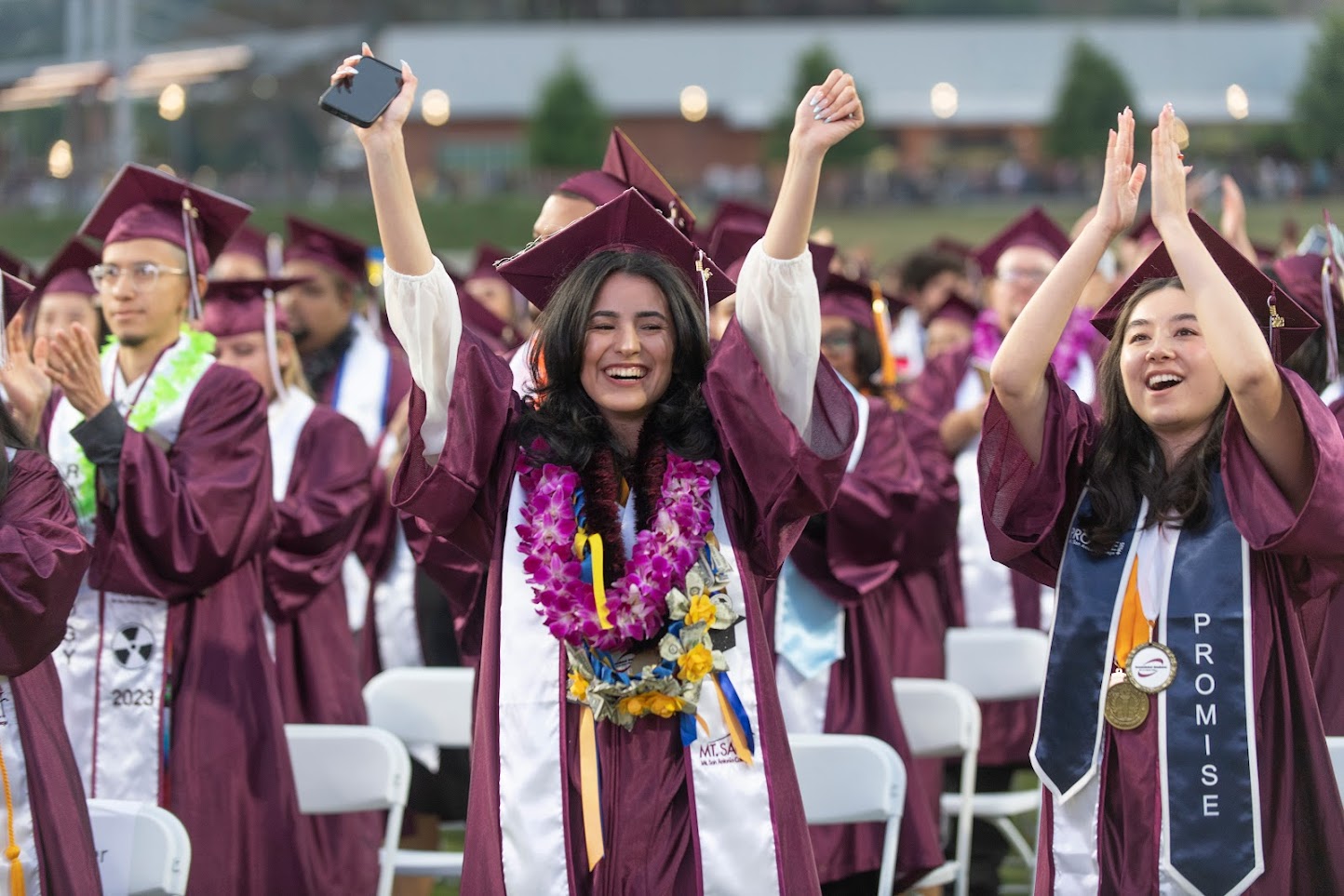 Three females dressed in graduation regalia smiling