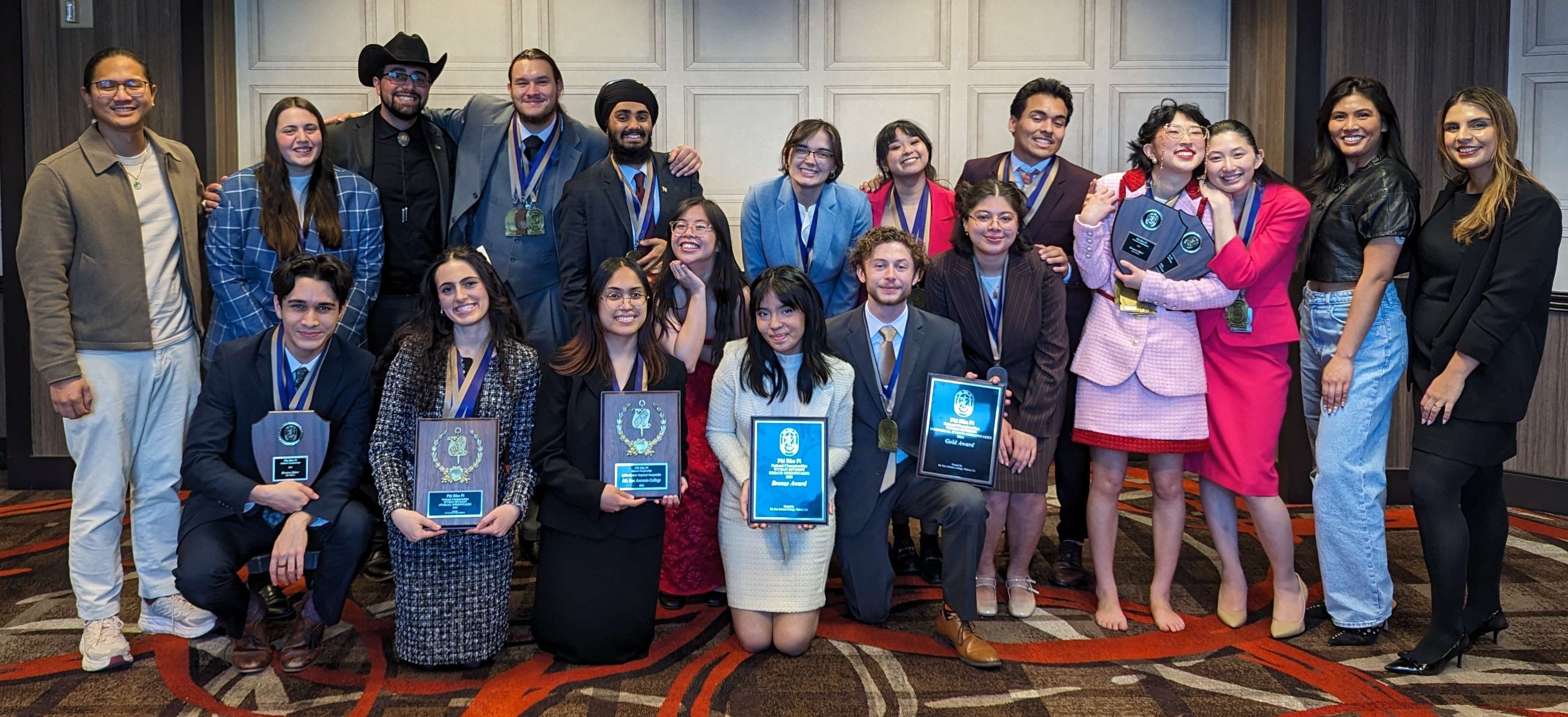 Group of students displaying plaques and trophies