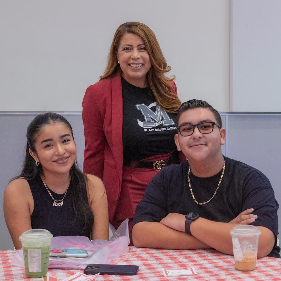Dr Garcia, smiling, stands behind two students, one male one female