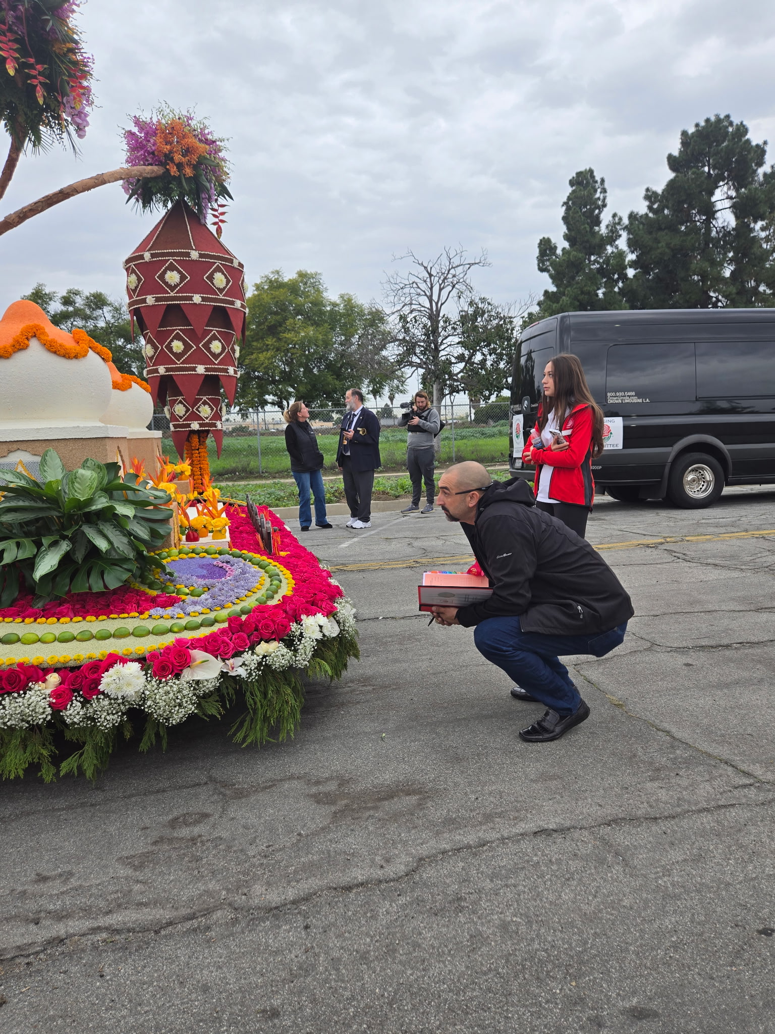 Chaz Perea bends down in front of a flower-covered float