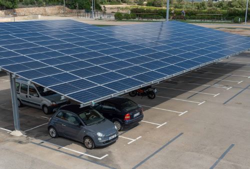 Two cars parked under canopy-mounted solar panels