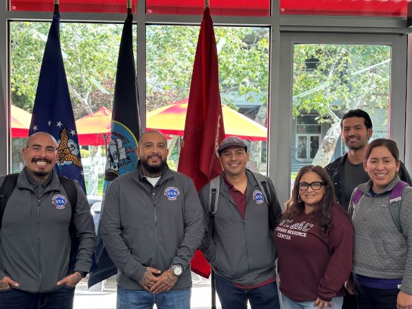 Group of men and women standing in front of military flags