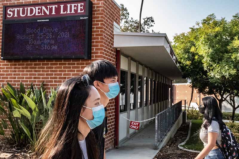 Students wearing masks cross campus