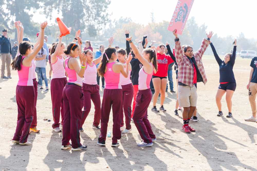 Women's XC hold thier arms up in victory