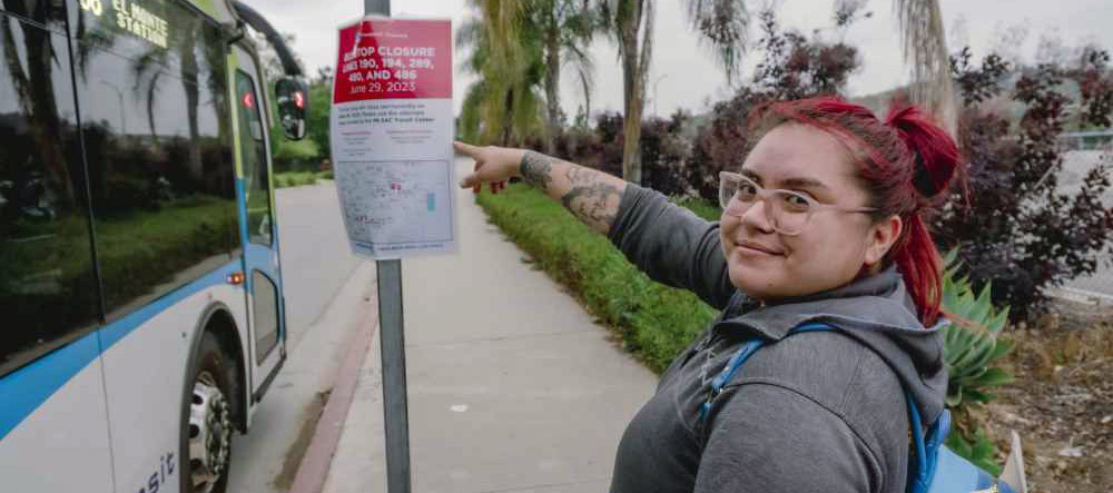 Bus rider motions to notice of bus stop closures next to bus