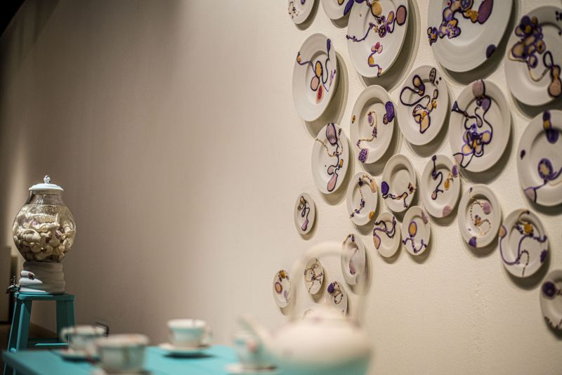 Plates on wall, a tea set in the foreground, with the beverage dispenser in the back