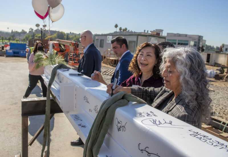 Judy Chen Haggerty laughs as Laura Santos signs beam