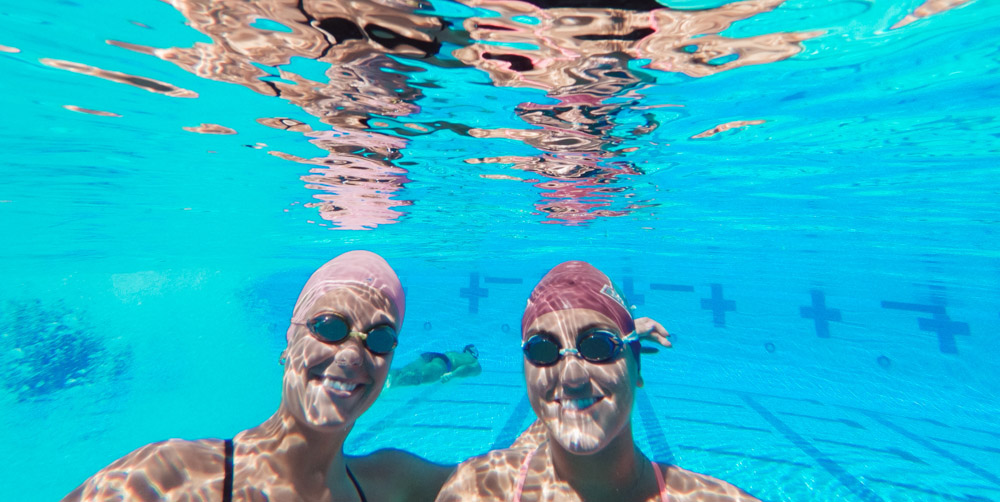 Paige Fast (L) and Madison Dorsey underwater at the Aquatics Center. 