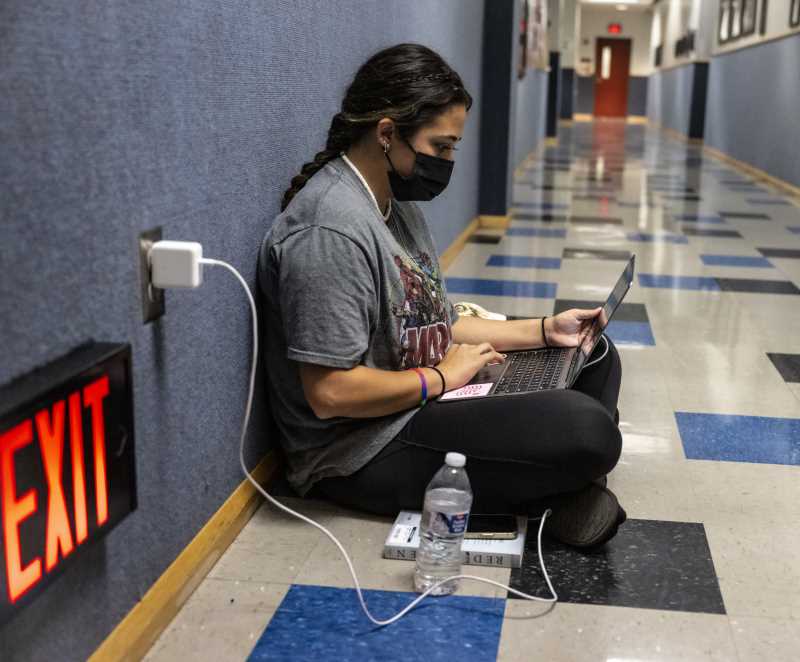 Student studies with her laptop plugged in hallway