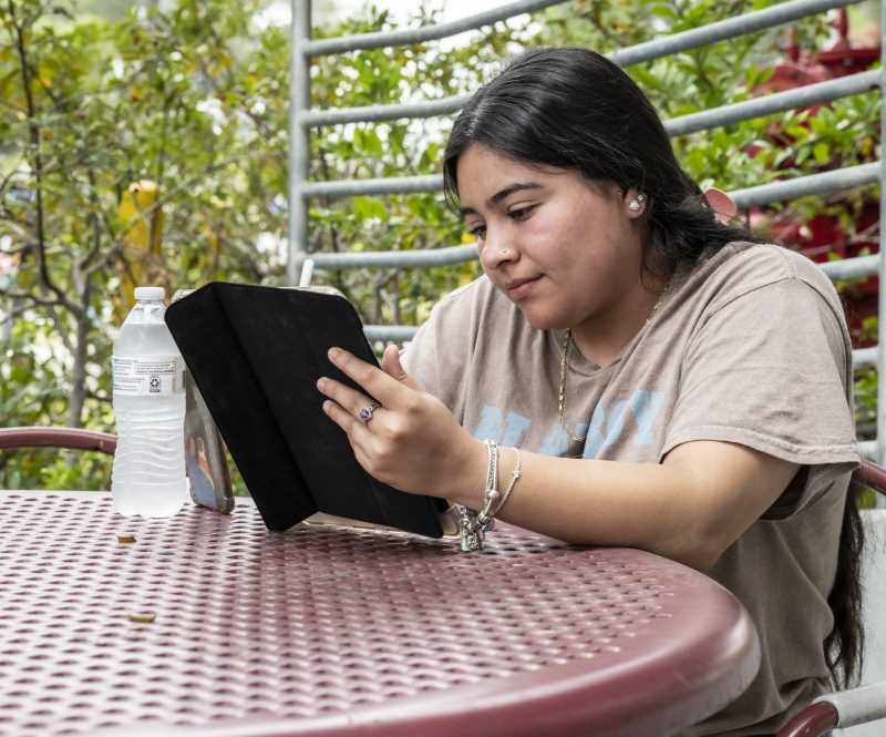 Student on her tablet outside of the Bldg. 61 convenience store.