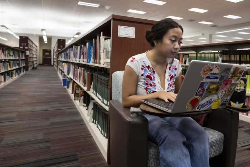 Student on her laptop with rows of books in the background