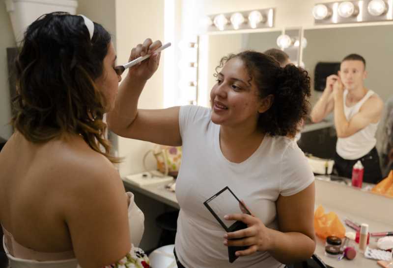 Student applies makeup to model's eyes