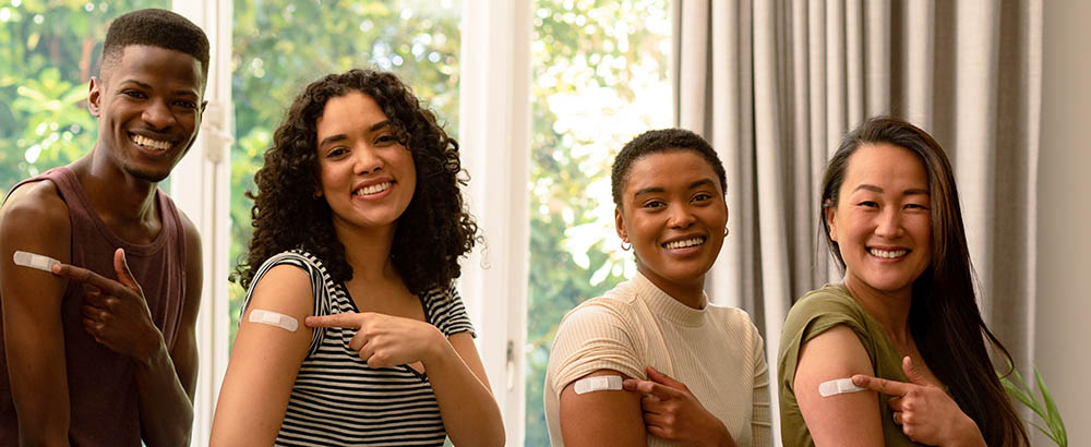 Four people point to bandages on their arms