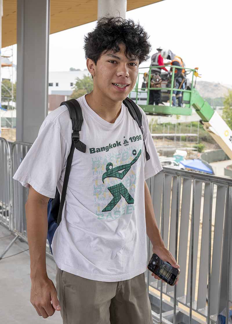 Student on Pedestrian Bridge with construction crew in background 