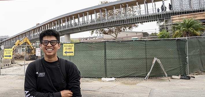 Student smiles while Pedestrian Bridge travels over his head