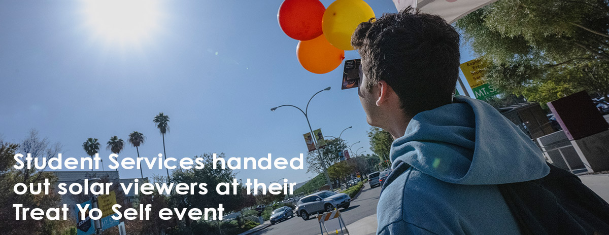 "Student Services handed out solar viewers at their Treat Yo Self event" - student looks up through viewer